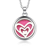 Silver necklace diffuser pendant with nested heart designs on a pink background