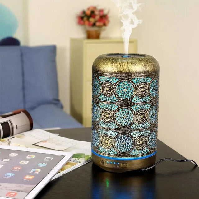 Decorative bronze essential oil diffuser with turquoise pattern emitting steam