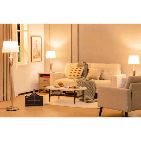 Cream-colored sofa with throw pillows and blanket beside a Brushed Silver Lamp Set