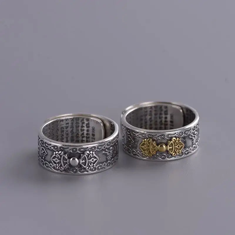 Two ornate sterling silver Buddha mantra rings with detailed engravings and gold accents