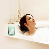 Person relaxing in a bathtub with Cedar Balsam scented soy candle and turquoise candle