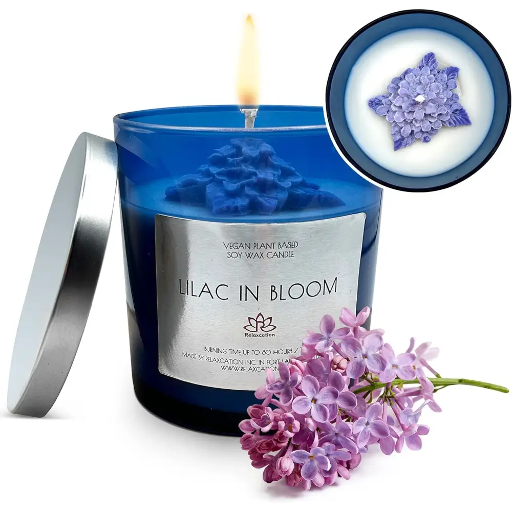 Blue scented soy candle labeled Lilac in Bloom with lilac flowers beside it