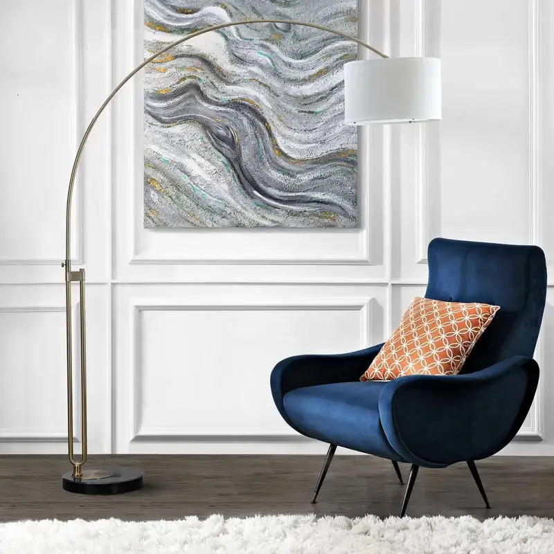 Navy blue velvet armchair with metal legs beside Elegant Joan Arched Floor Lamp