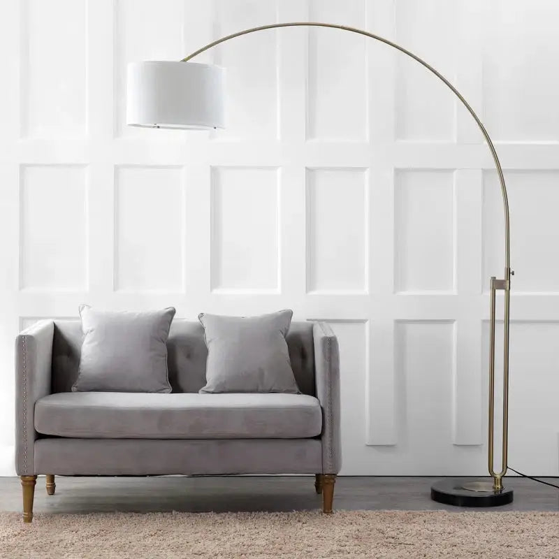 Elegant Joan Arched Floor Lamp featuring a white drum shade and brass-finished stem