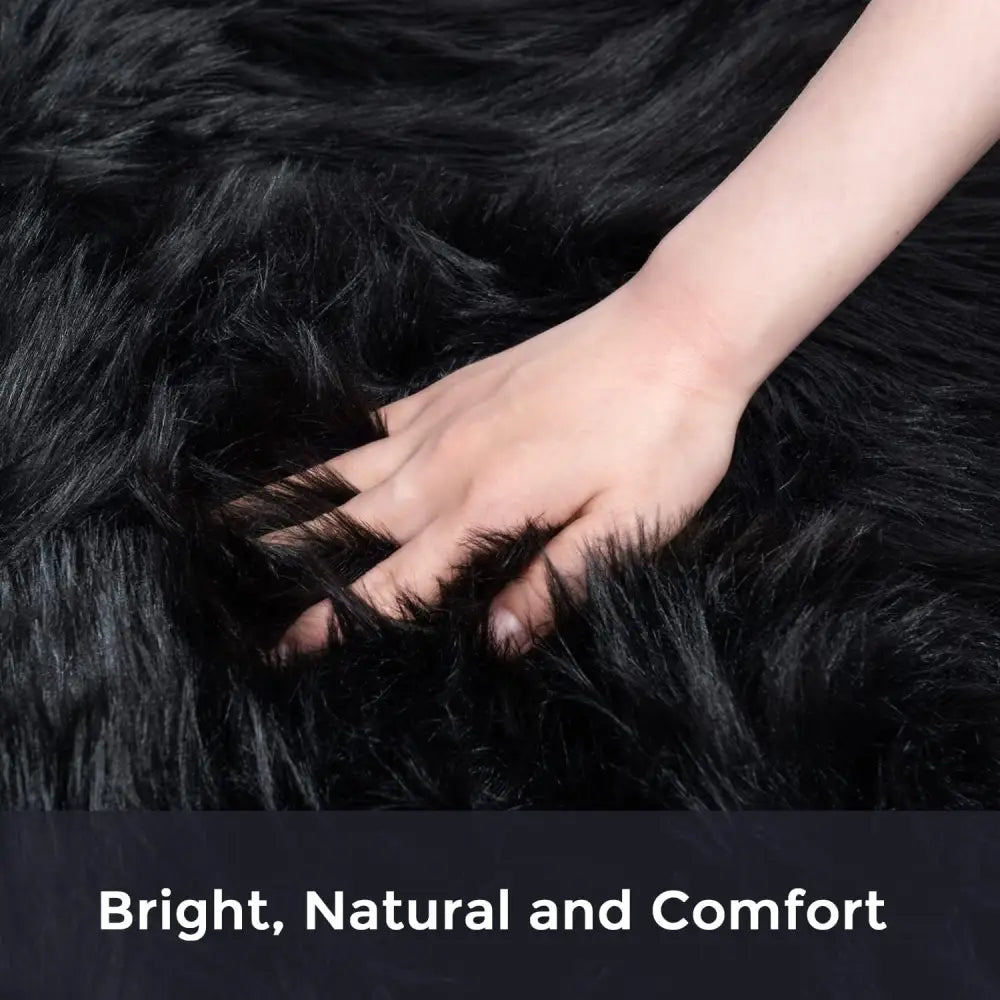 Fluffy faux sheepskin fur area rug with a hand touching the soft black surface