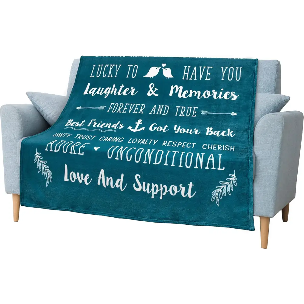 Teal throw blanket with friendship quotes draped over a gray couch for best friends