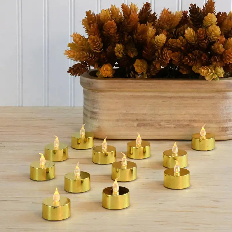 Gold LED tea lights arranged with red berry branches on a decorative surface