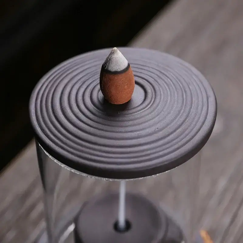 Spinning top-like handmade ceramic incense burner with circular ridges on the lid