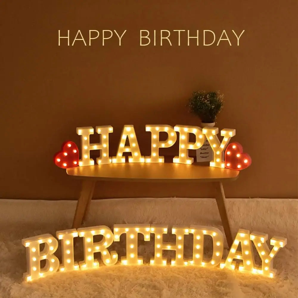 Illuminated marquee letters spelling Happy Birthday with decorative red mushroom lights