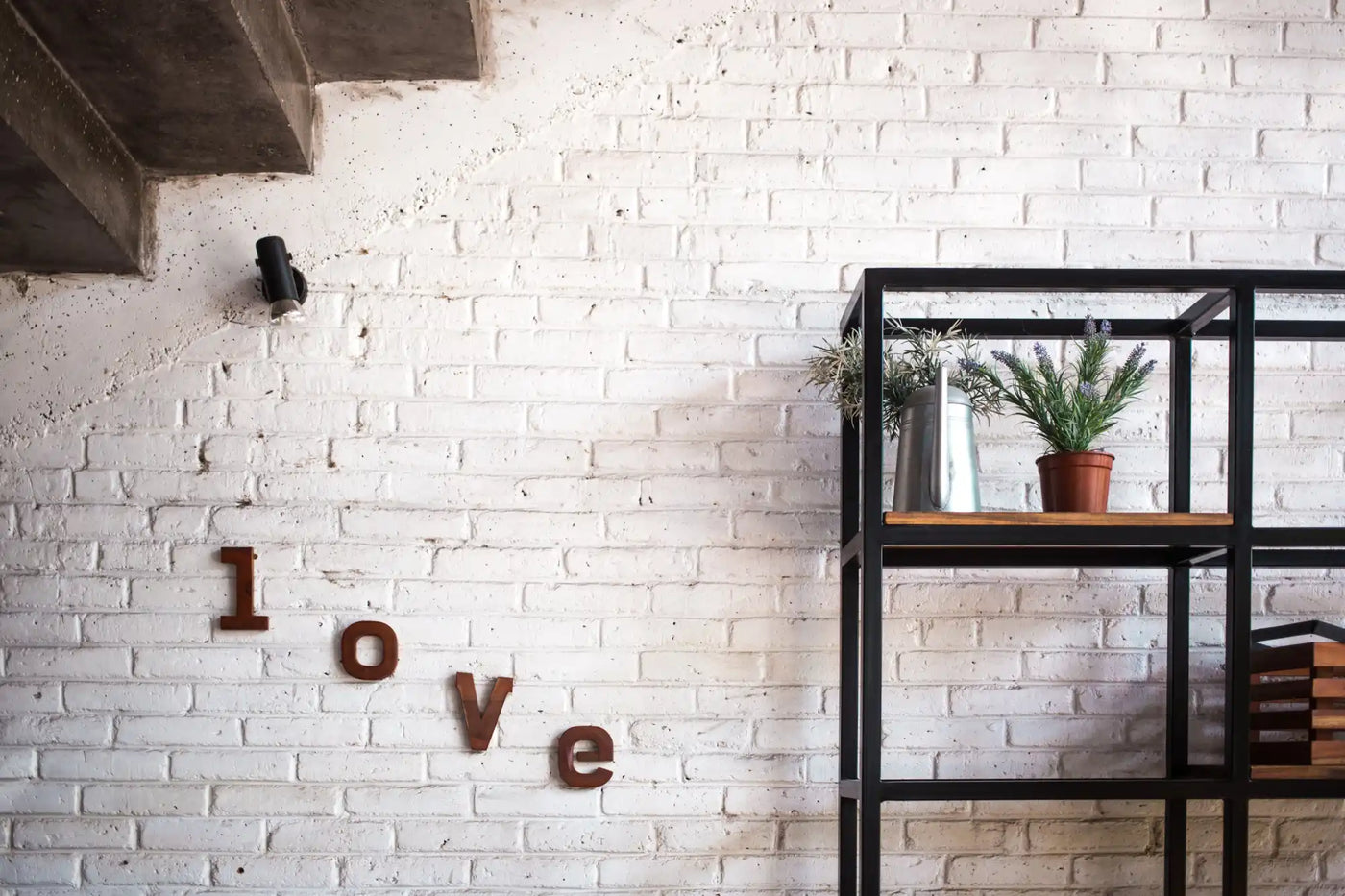 Letters spelling out ’love’ mounted on a white brick wall.