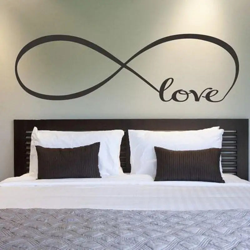 Infinity vinyl decal wall art featuring the word Love over a serene bed setting