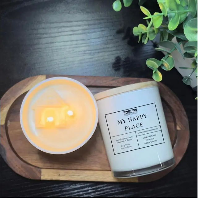 Lit white My Happy Place scented soy candle in a glass jar on a wooden tray