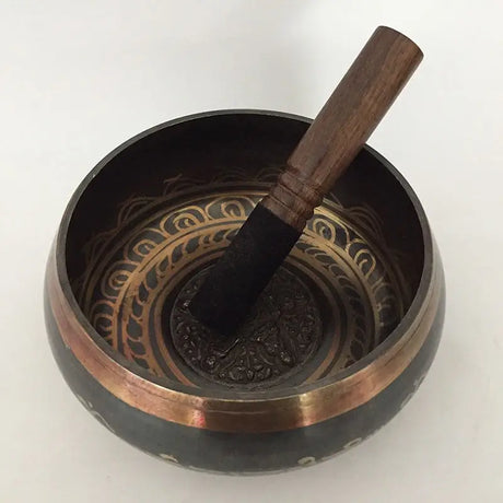 Tibetan singing bowl with wooden striker and decorative metallic patterns Himalayan hand-hammered