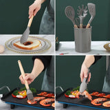 Silicone kitchen utensils set with wooden handles in a gray holder for cooking