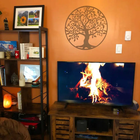 TV displaying a roaring campfire with Tree of Life wall decal for cozy ambiance