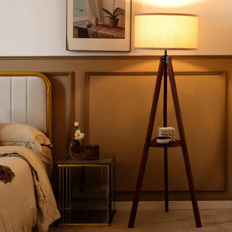 Tripod floor lamp with cream shade and circular shelf, ideal for stylish lighting decor