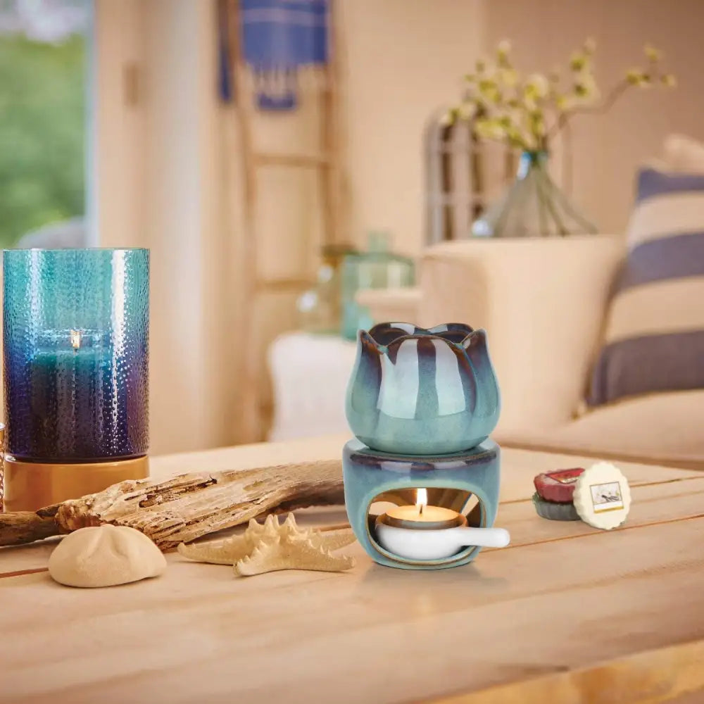 Turquoise ceramic oil burner with tea light candle and cutout design for ambiance