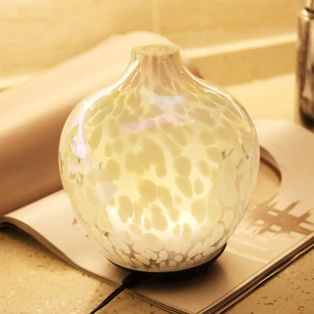 Glowing white designer glass aroma diffuser with textured marbled surface pattern