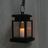 Black lantern with glowing candle in glass panels, a Waterproof LED Solar Outdoor Garden Lamp