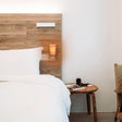 White bed with wooden headboard and Himalayan salt night light for a cozy ambiance